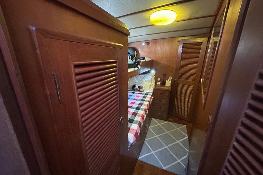 Cozy cabin interior of 1981 Ocean Alexander 50 Pilothouse with wooden furnishings and plaid bedding.