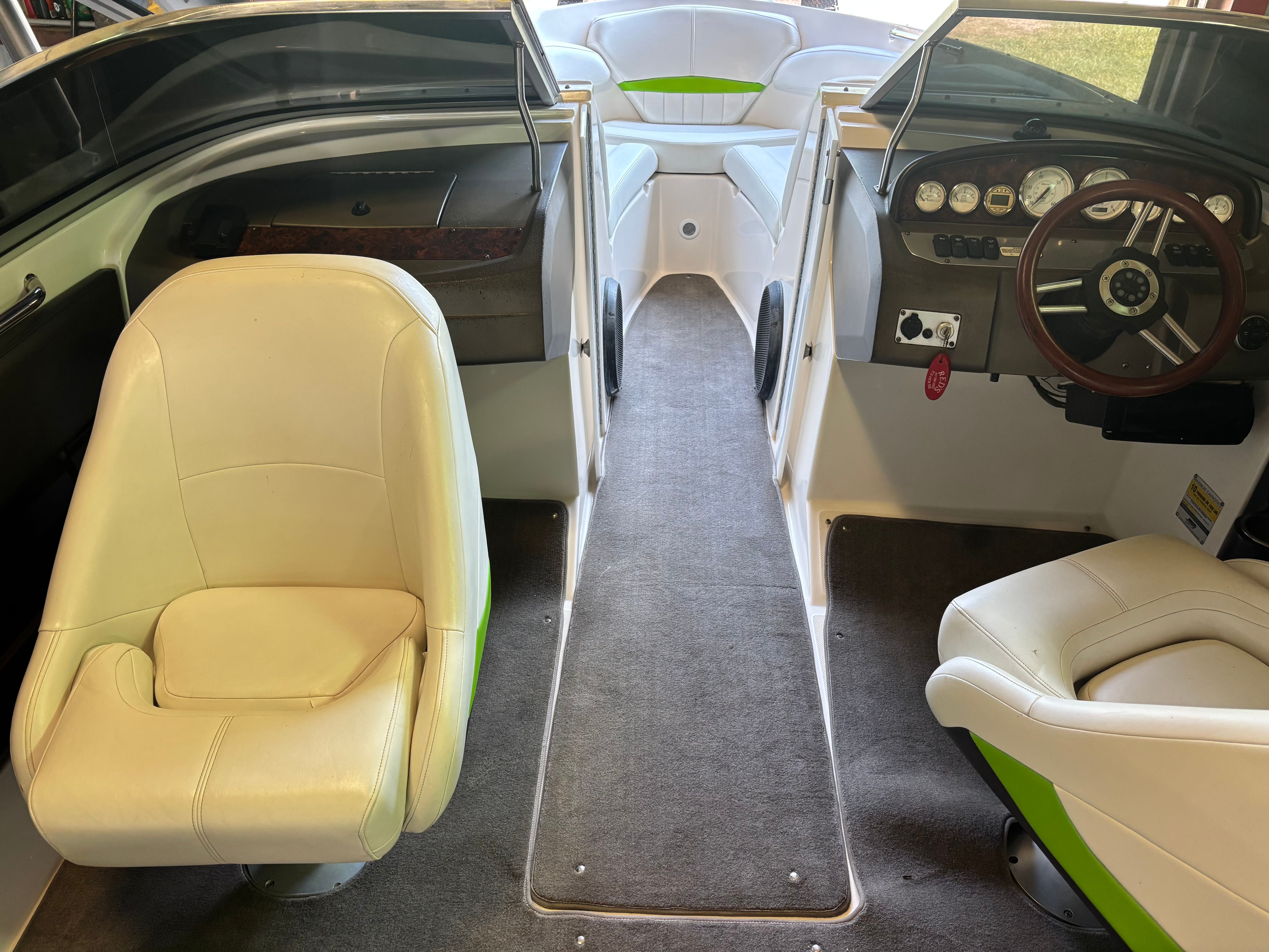 Interior of a 2006 Regal 2200 Bowrider with white seats and a wooden steering wheel.