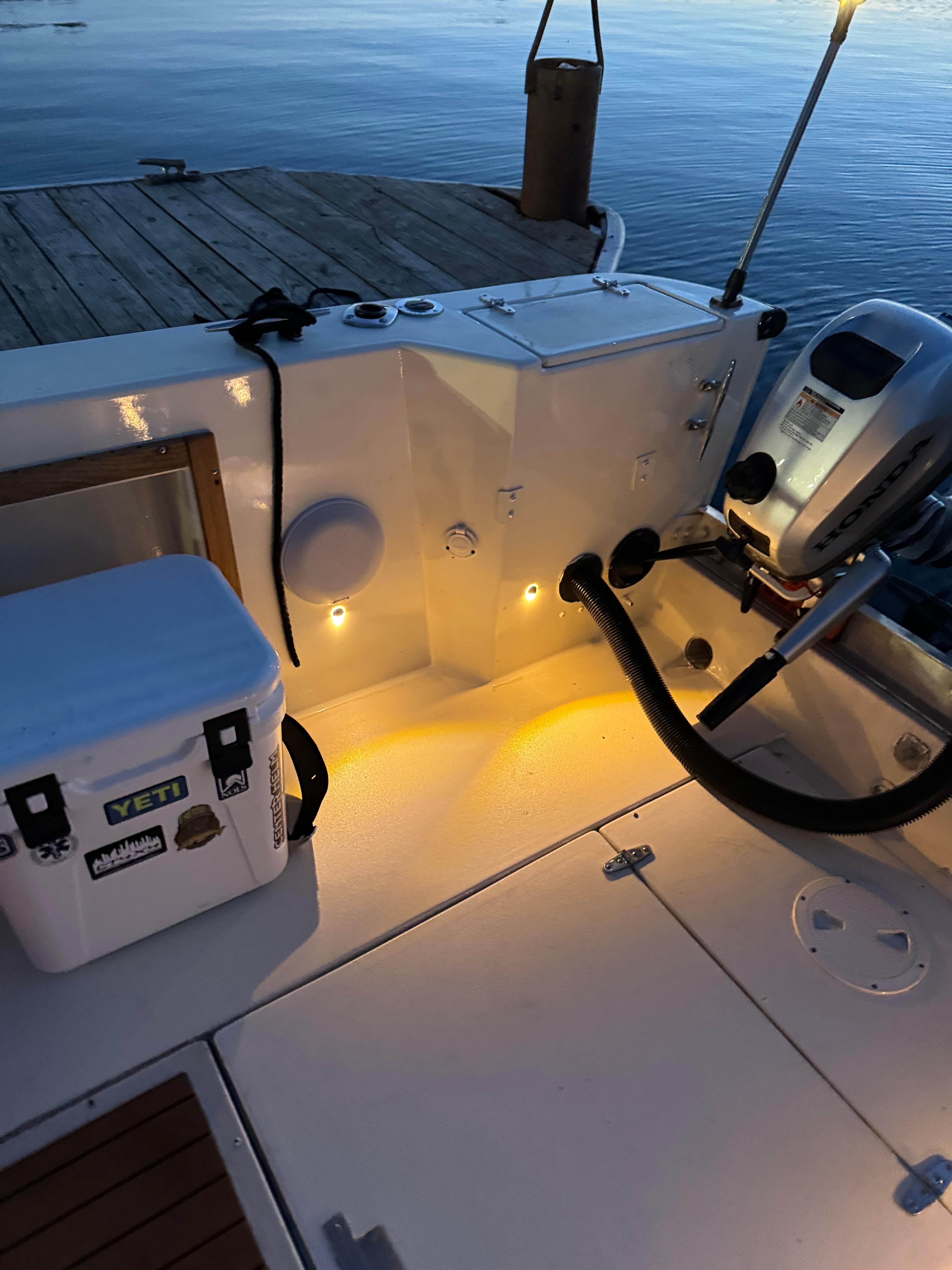 1987 Custom Biddison 2200 boat interior with cooler and motor, docked at sunset.