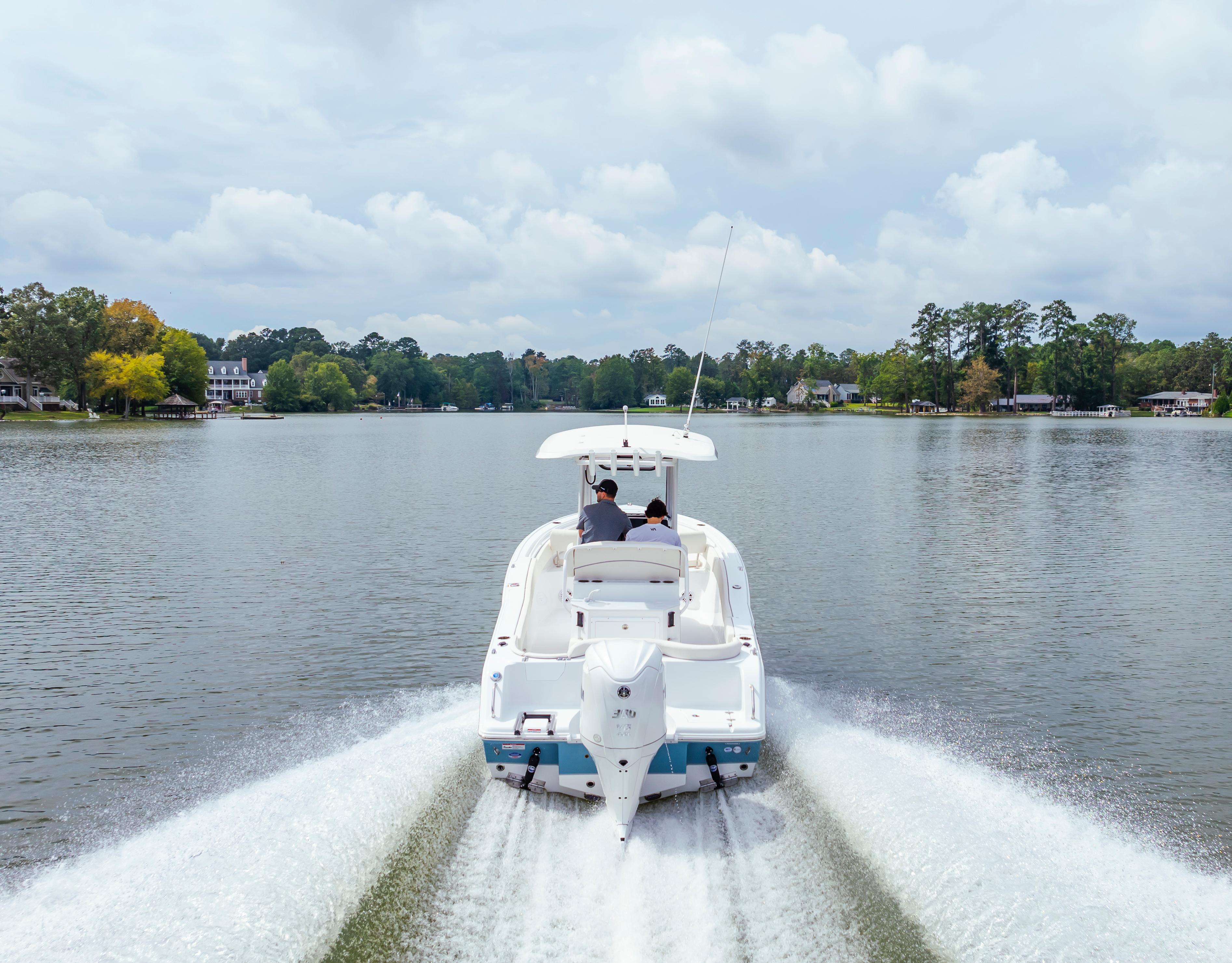 2026 Sea Hunt Ultra 245 SE cruising on a serene lake with lush surroundings.