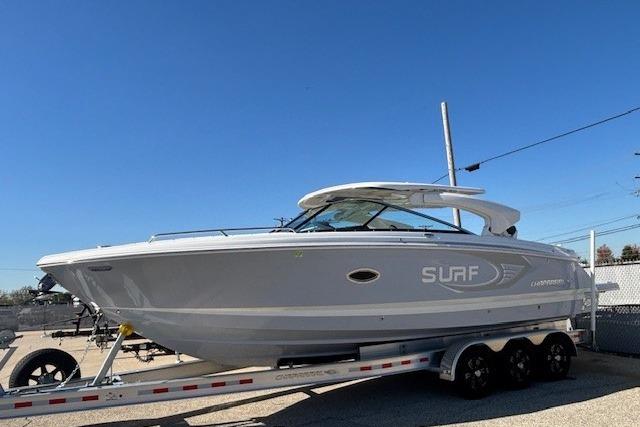 2024 Chaparral 30 Surf boat on a trailer, displayed outdoors under clear blue sky.