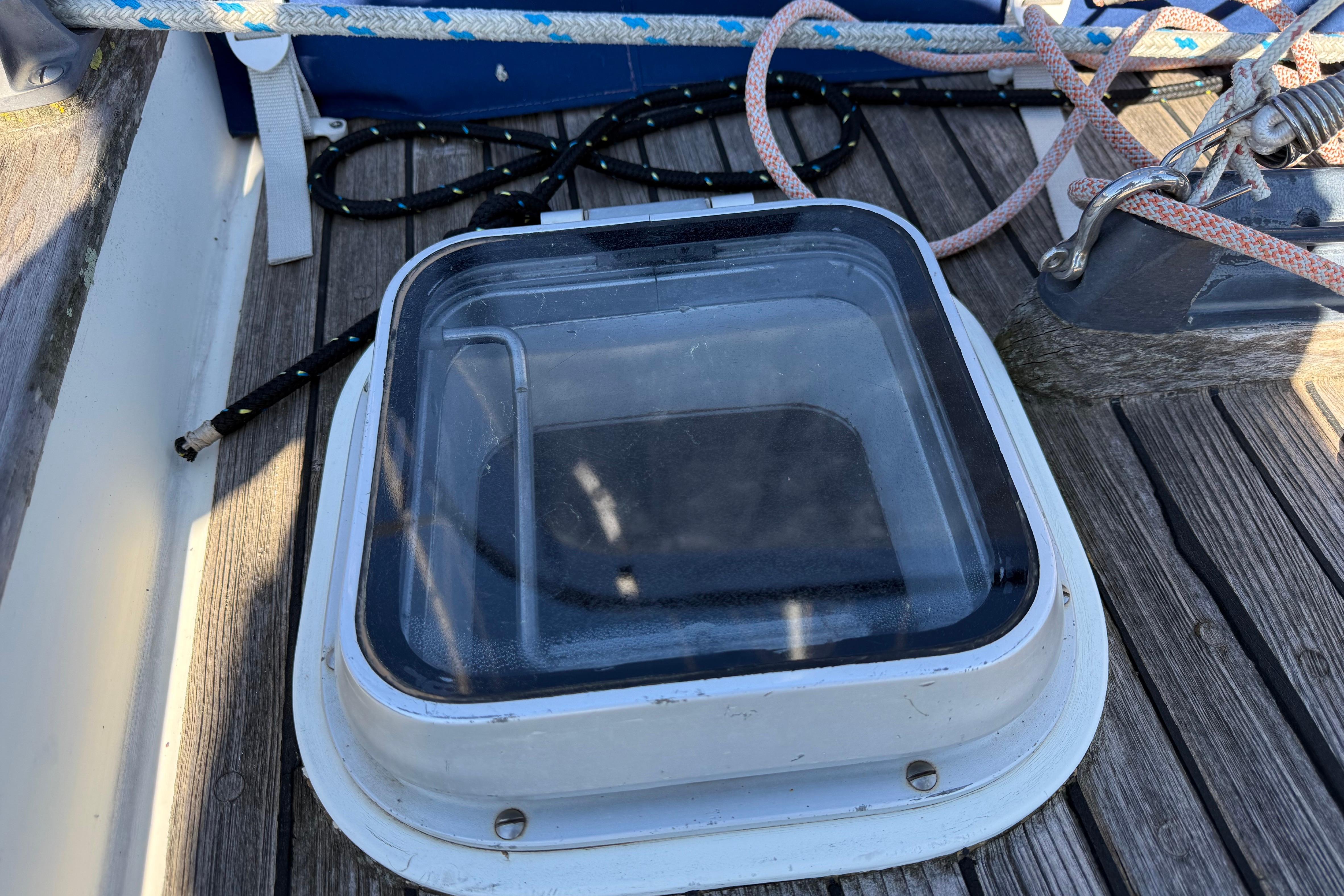 Deck hatch on 1983 Moody 134 Grenadier sailboat with ropes and wooden surface.