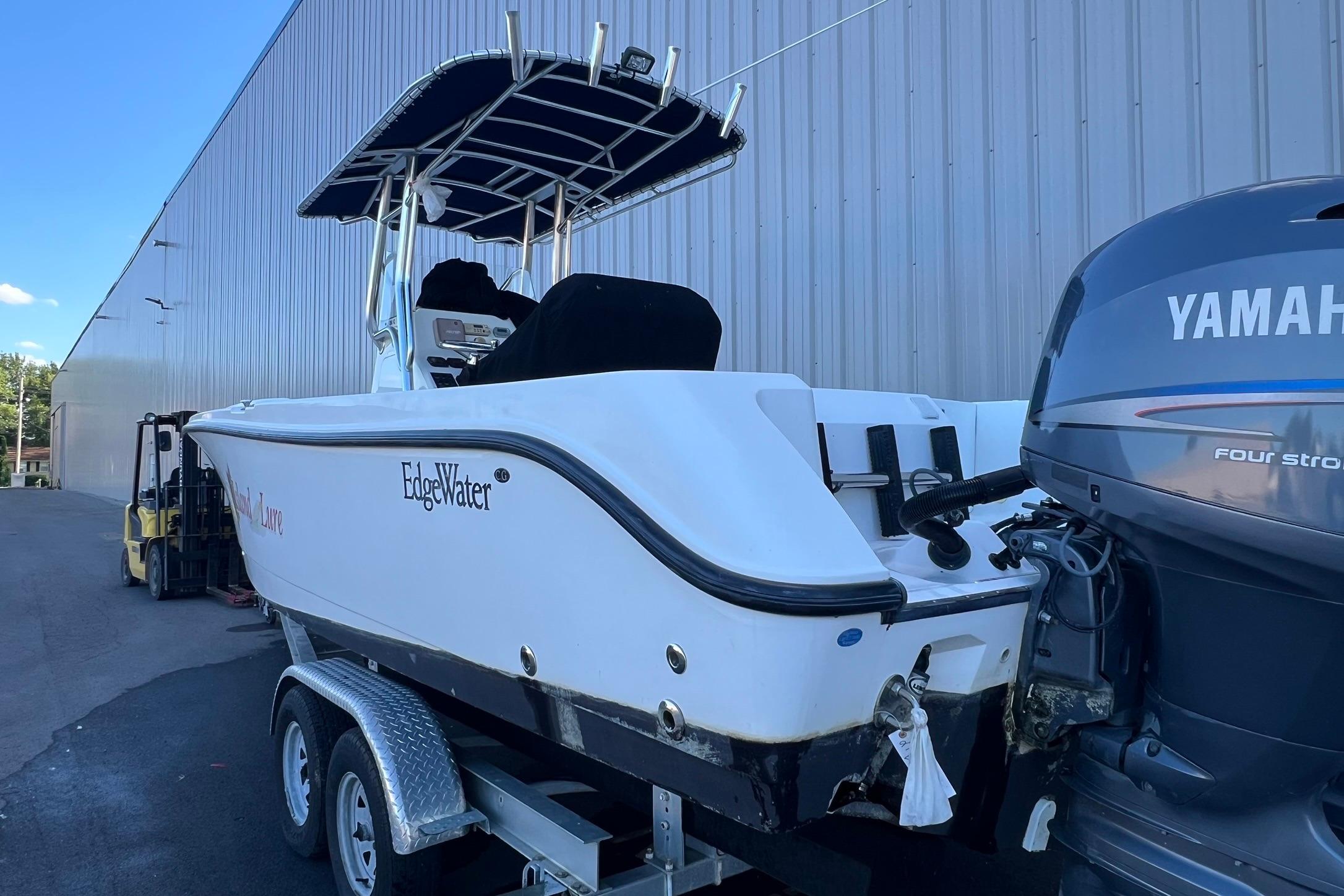 2006 Edgewater 245CC boat with Yamaha engine on trailer, parked by a warehouse.