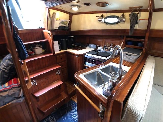 1979 Hans Christian 38 MKII yacht interior with wooden cabinetry and compact kitchen area.