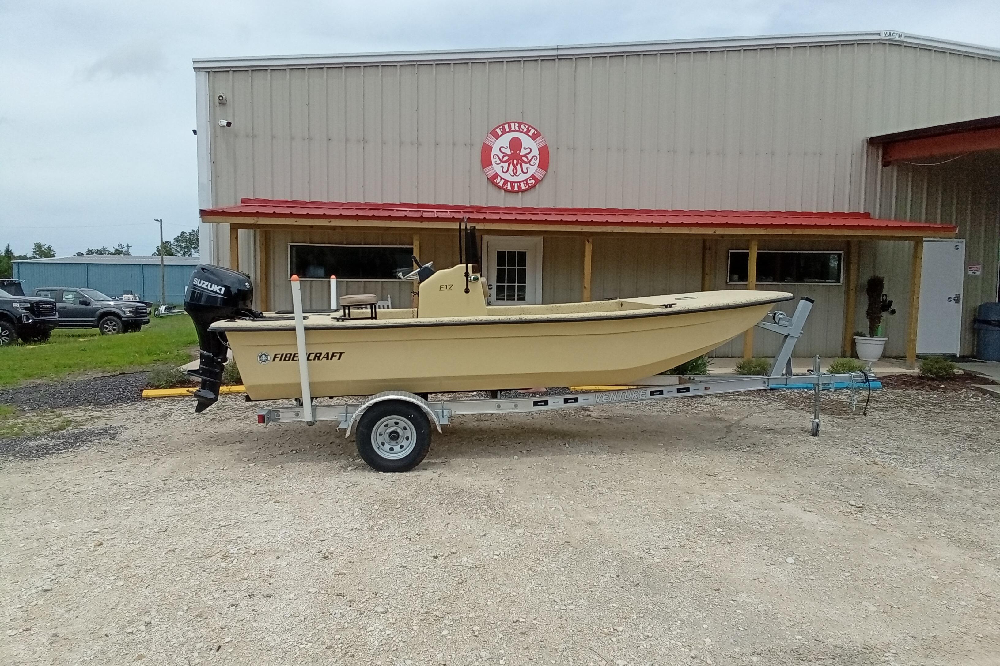 2025 Fibercraft F17 boat on trailer outside a metal building with red roof.