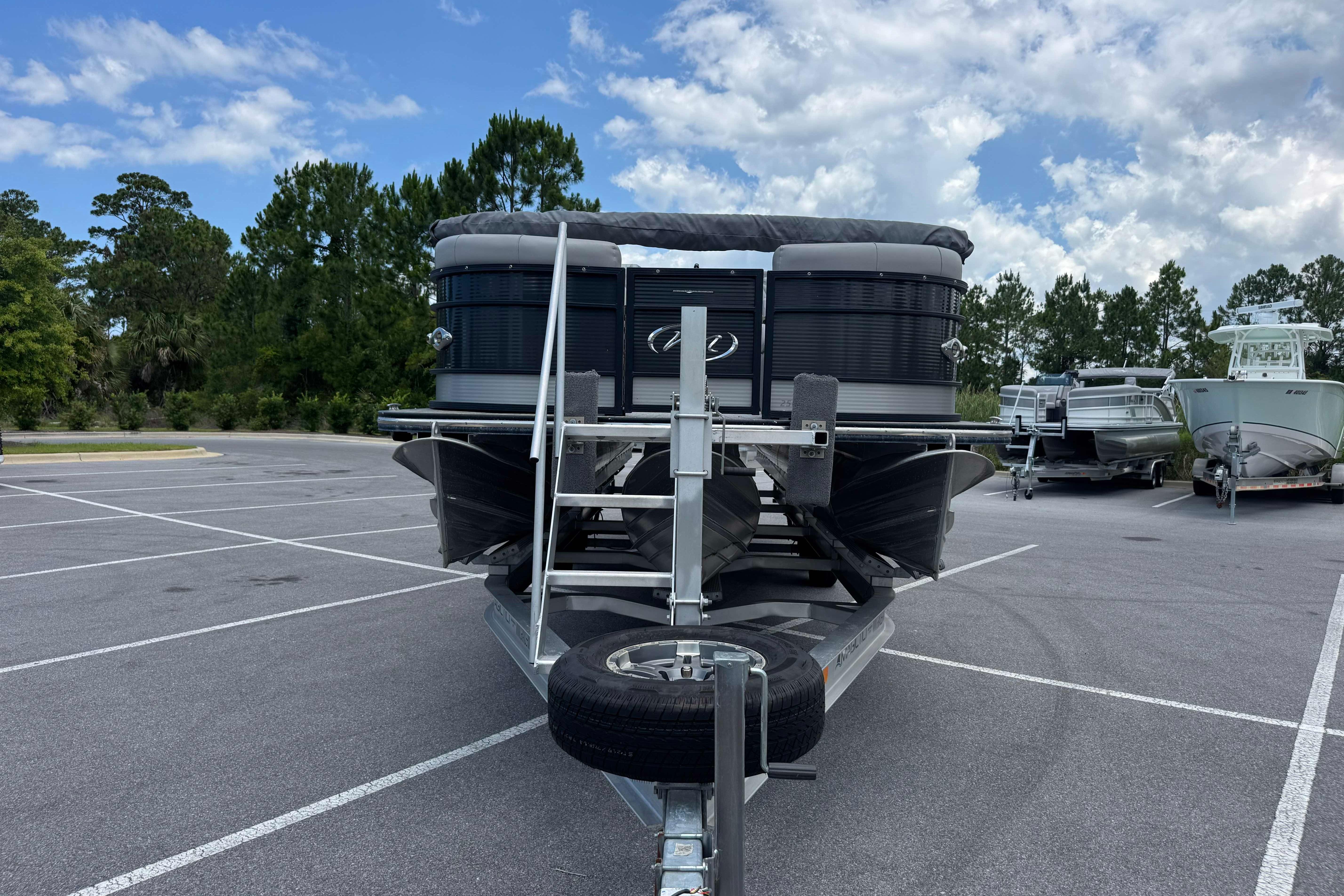 2022 Manitou 25 Encore pontoon boat on trailer in parking lot.
