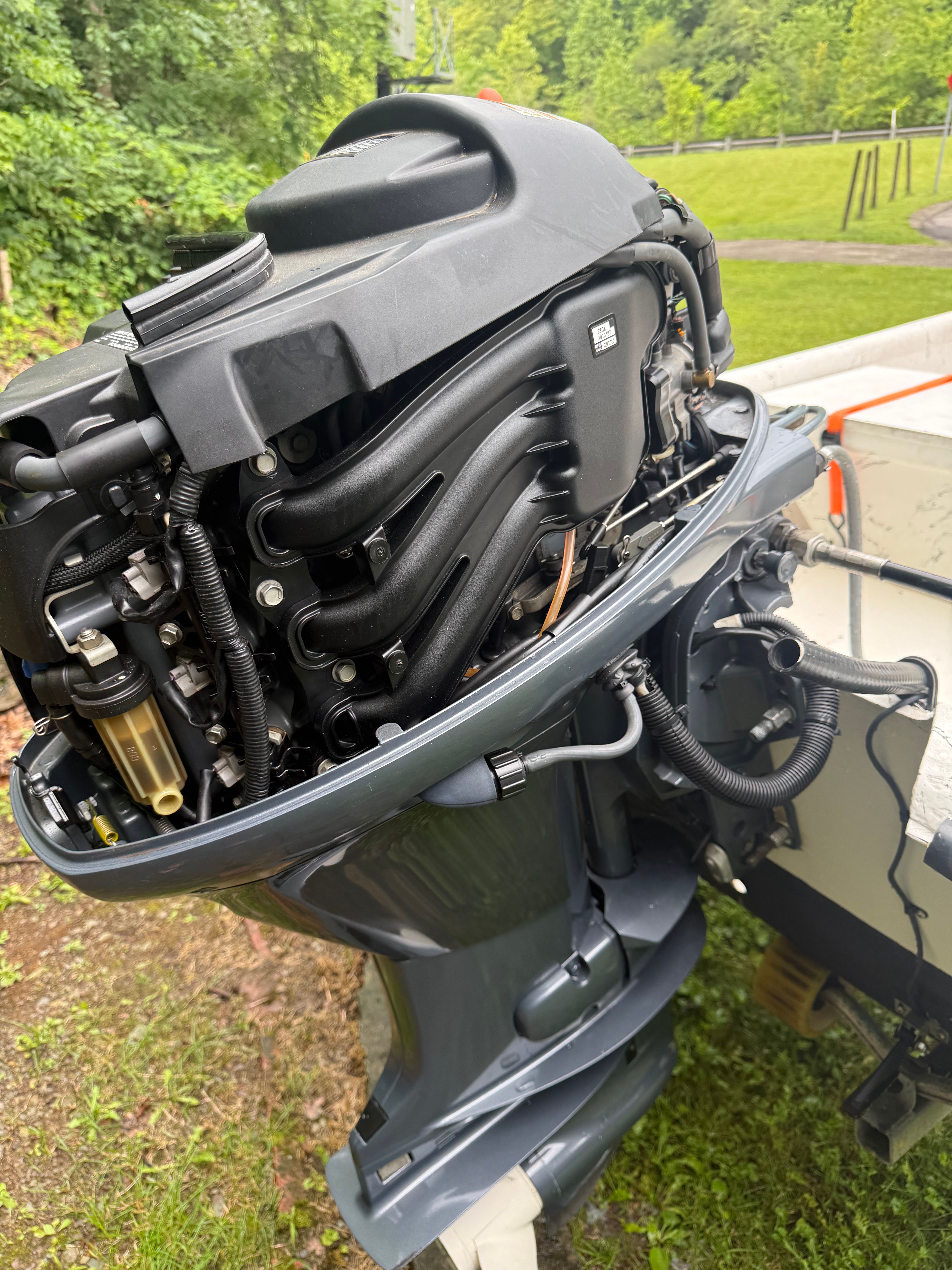 An outboard motor of a boat, surrounded by green vegetation.