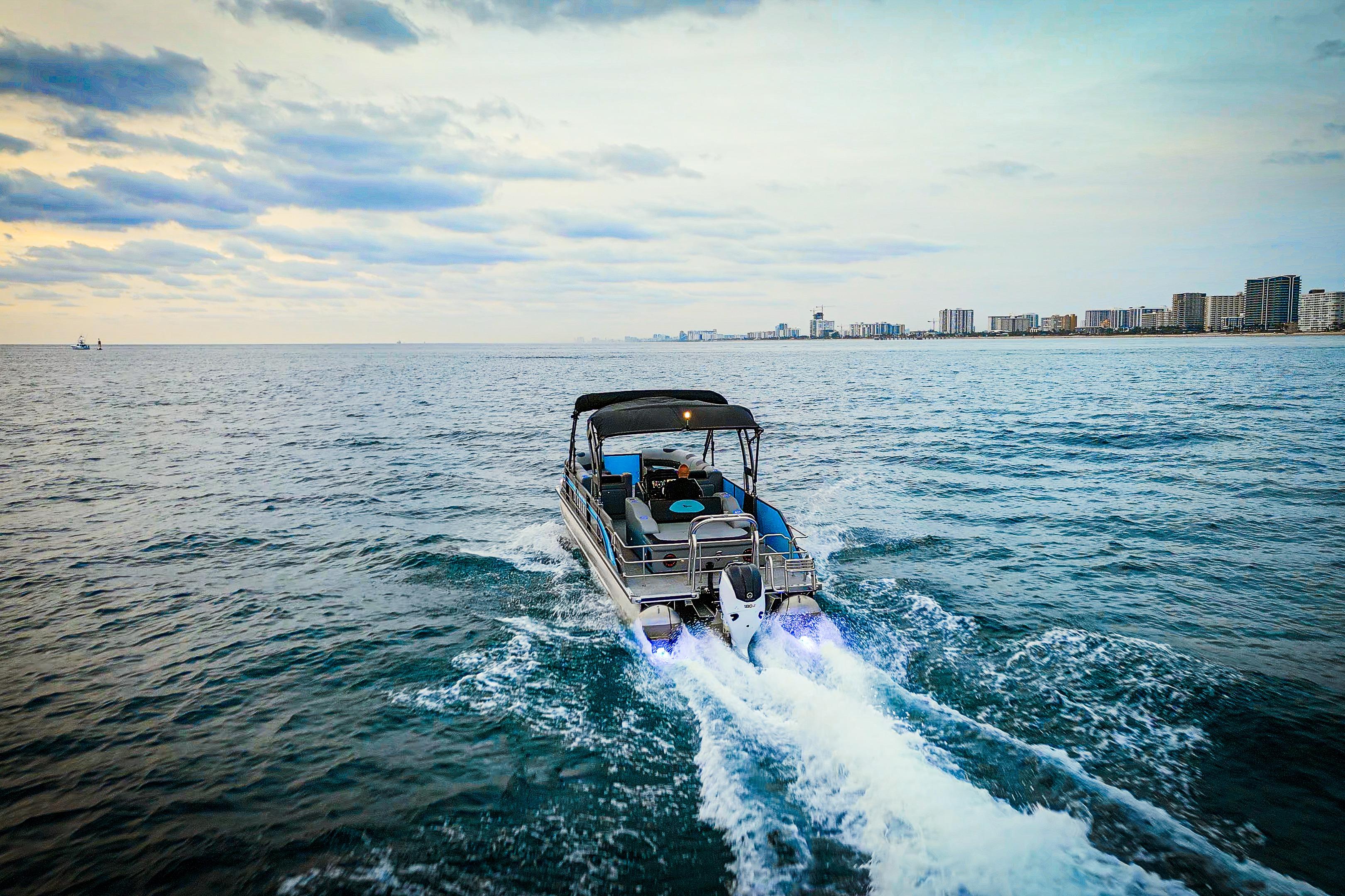 2025 Vision Marine Technologies V30 boat cruising on open water near city skyline.