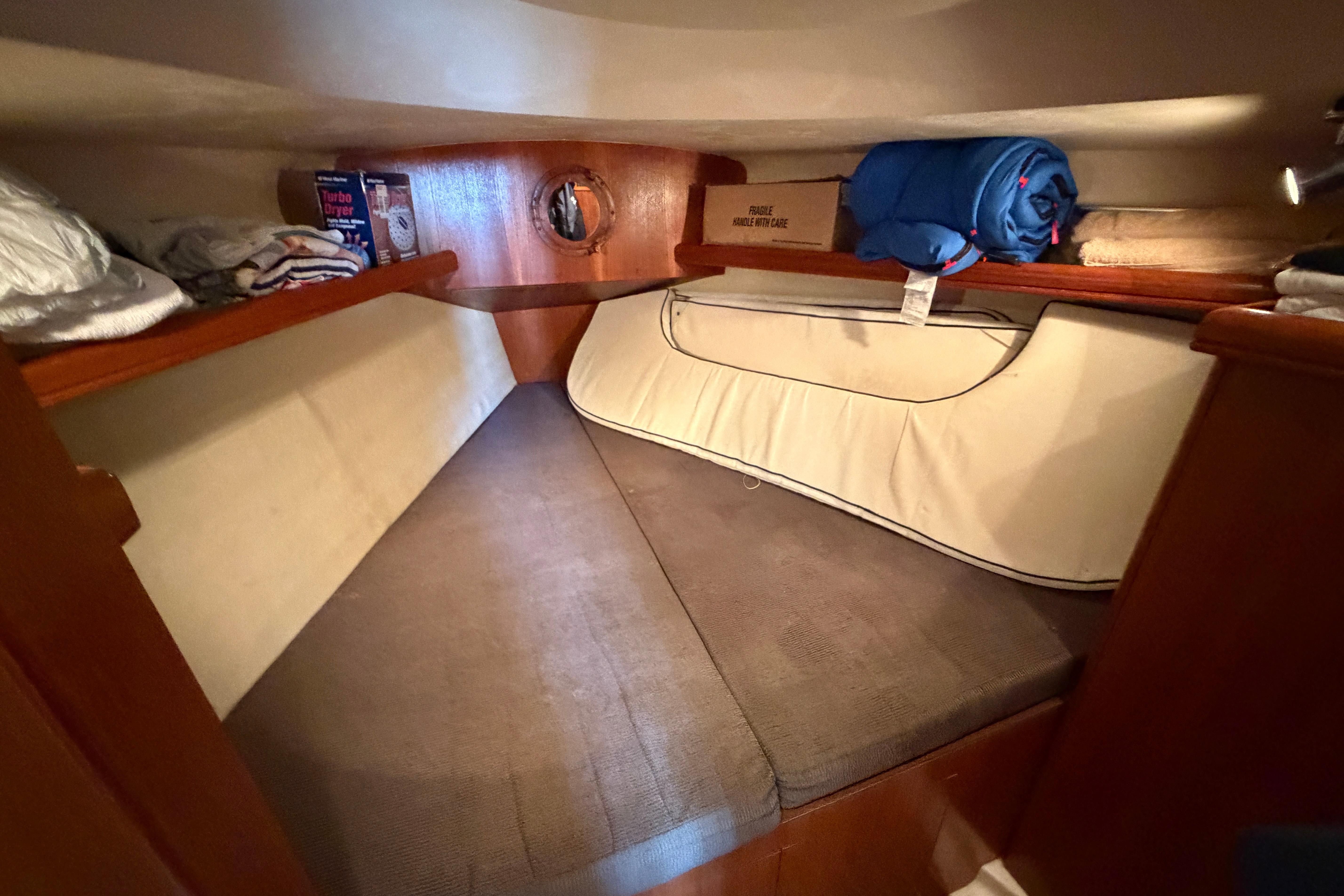 Cozy cabin interior of a 2005 Hunter 38 sailboat with storage and bedding.