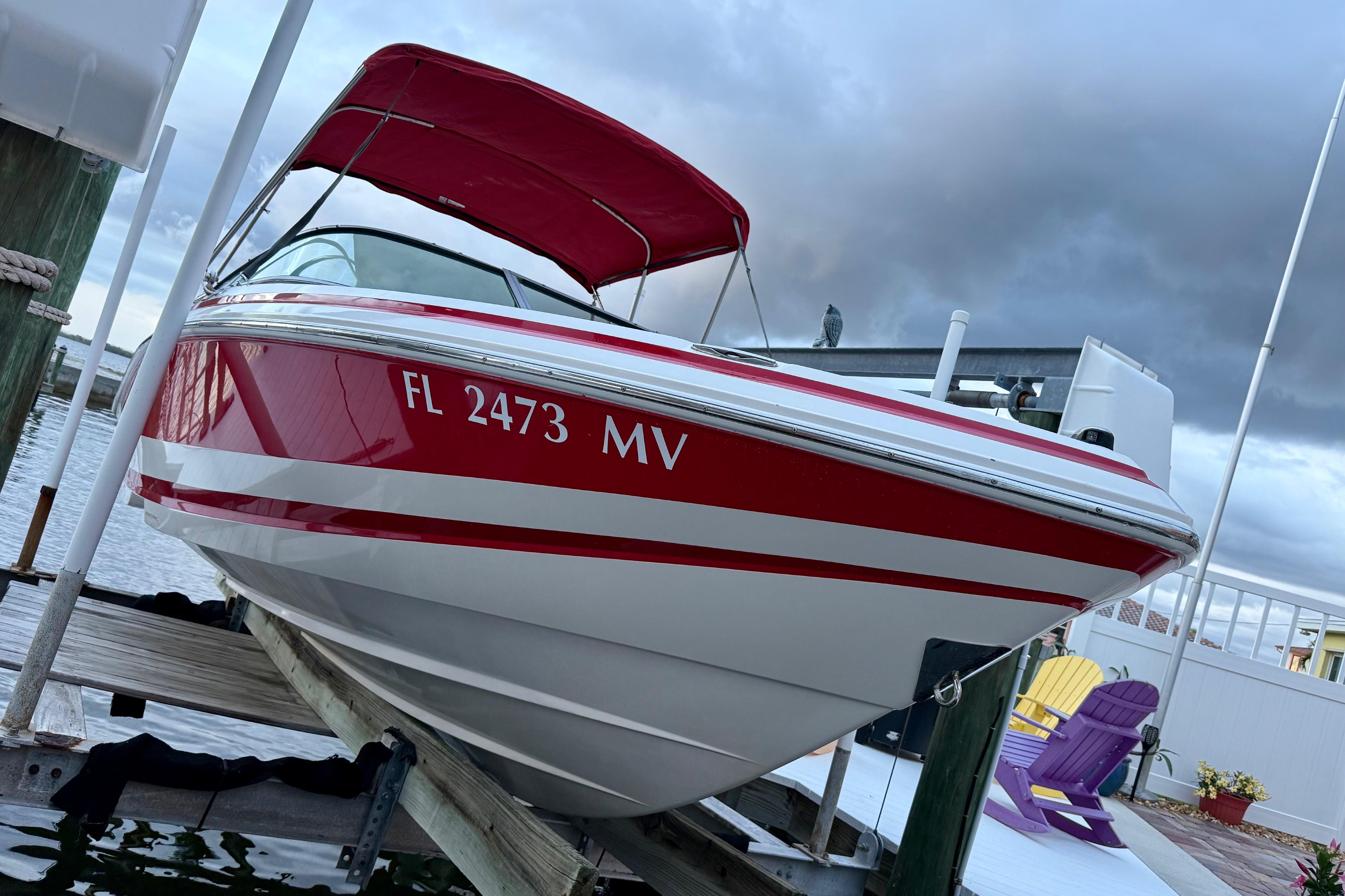 Red and white 2004 Regal 2000 Bowrider boat docked, featuring a canopy and registration number.