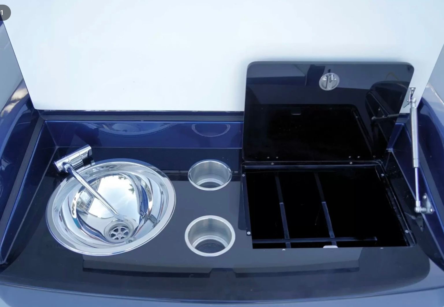 A modern boat galley module with a sink, two cup holders, and a closed storage compartment.