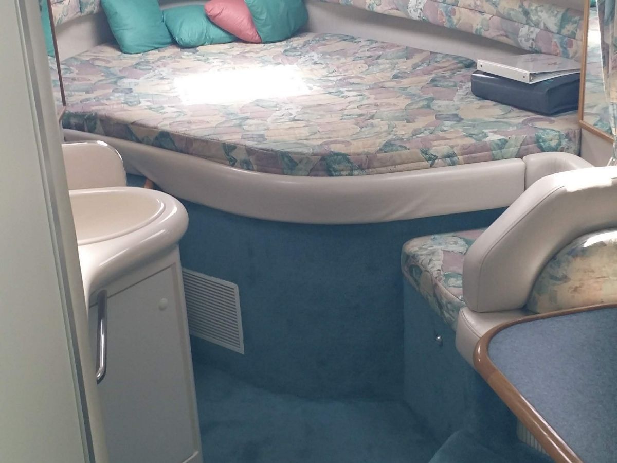 Interior of a 1995 Sea Ray Sundancer 330 with a cozy bed and seating area.