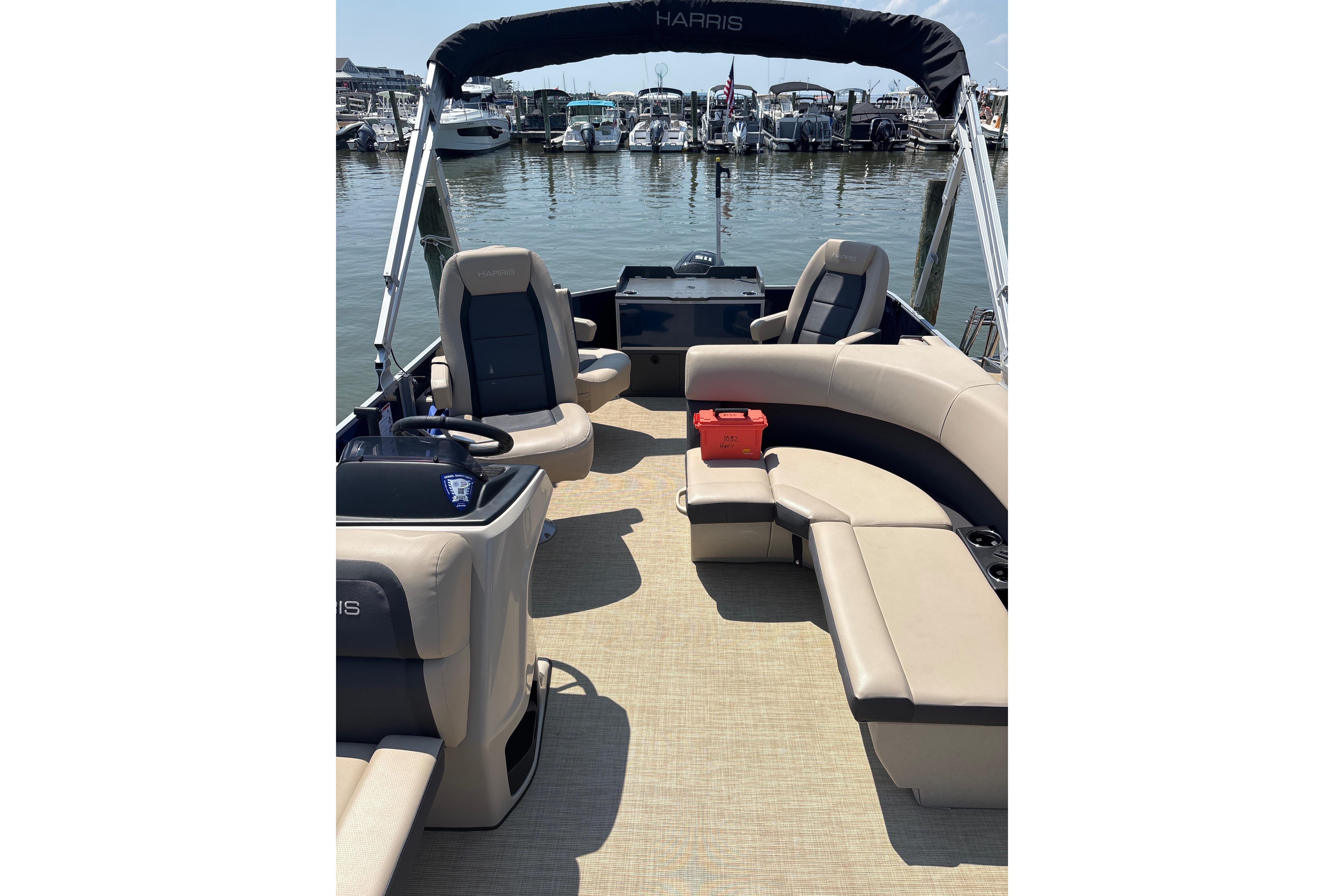 2025 Harris Cruiser 230 pontoon boat interior with beige seating at marina.