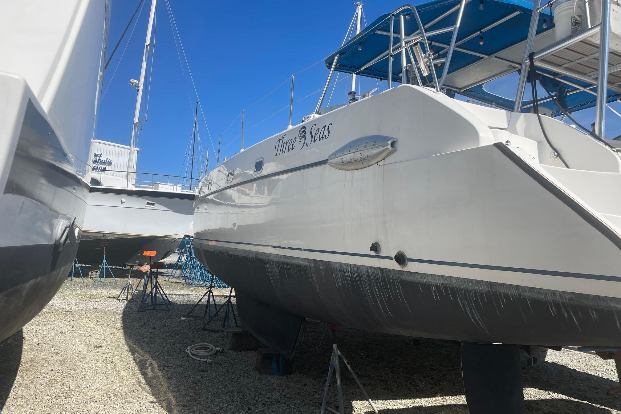 2002 Fountaine Pajot Belize 43 catamaran on dry dock, named "Three Seas," under clear blue sky.