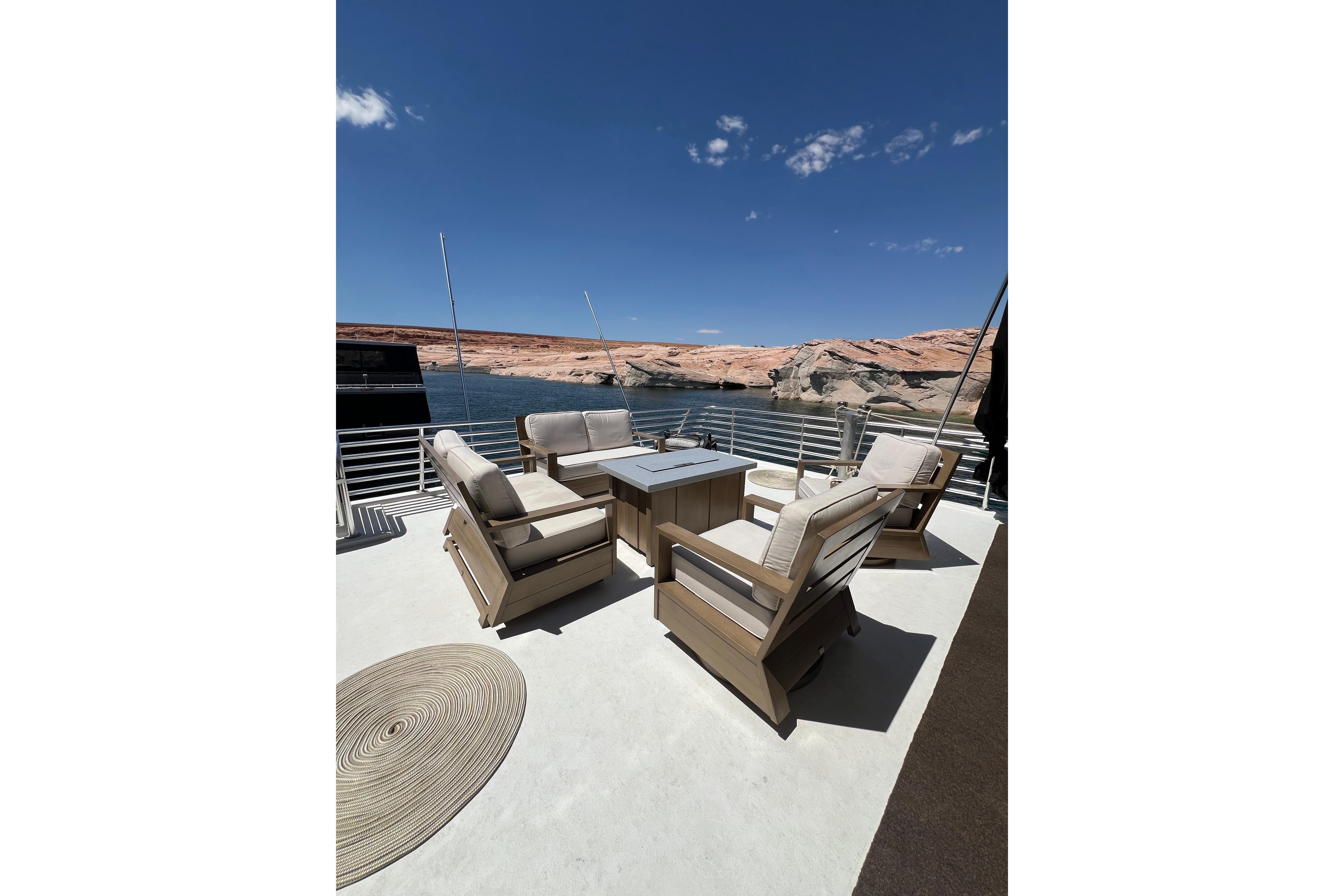 Luxurious Sumerset 2025 houseboat deck with comfortable seating, overlooking serene waters and rocky landscape.