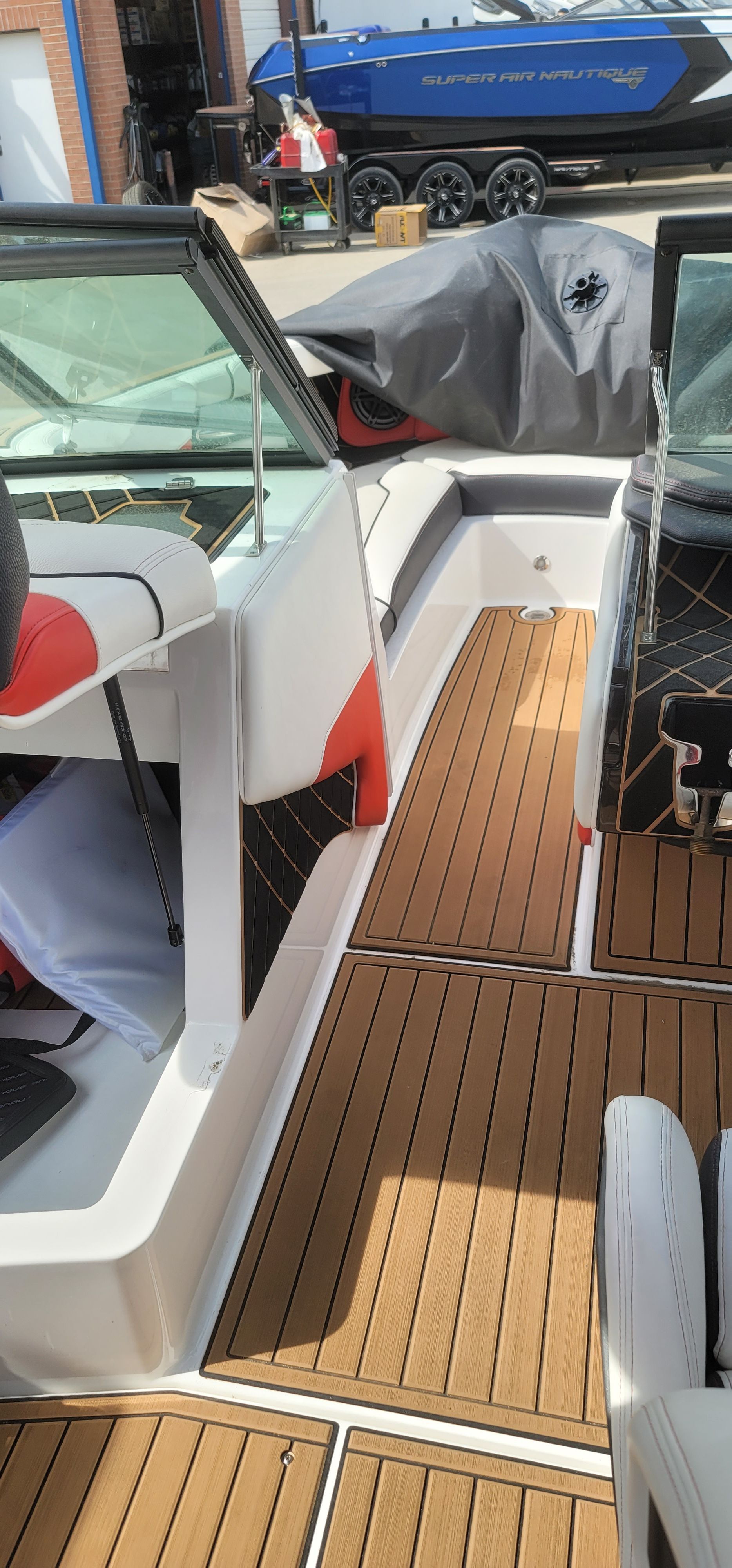 The image shows the cockpit of a 2019 Nautique Super Air Nautique GS22 with wood flooring and modern seating.