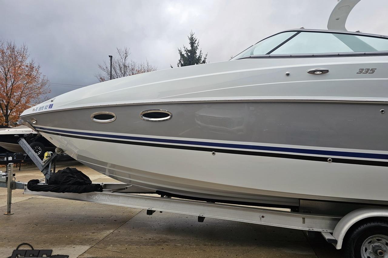 2008 Baja 335 Performance boat on trailer, parked outdoors under cloudy sky.