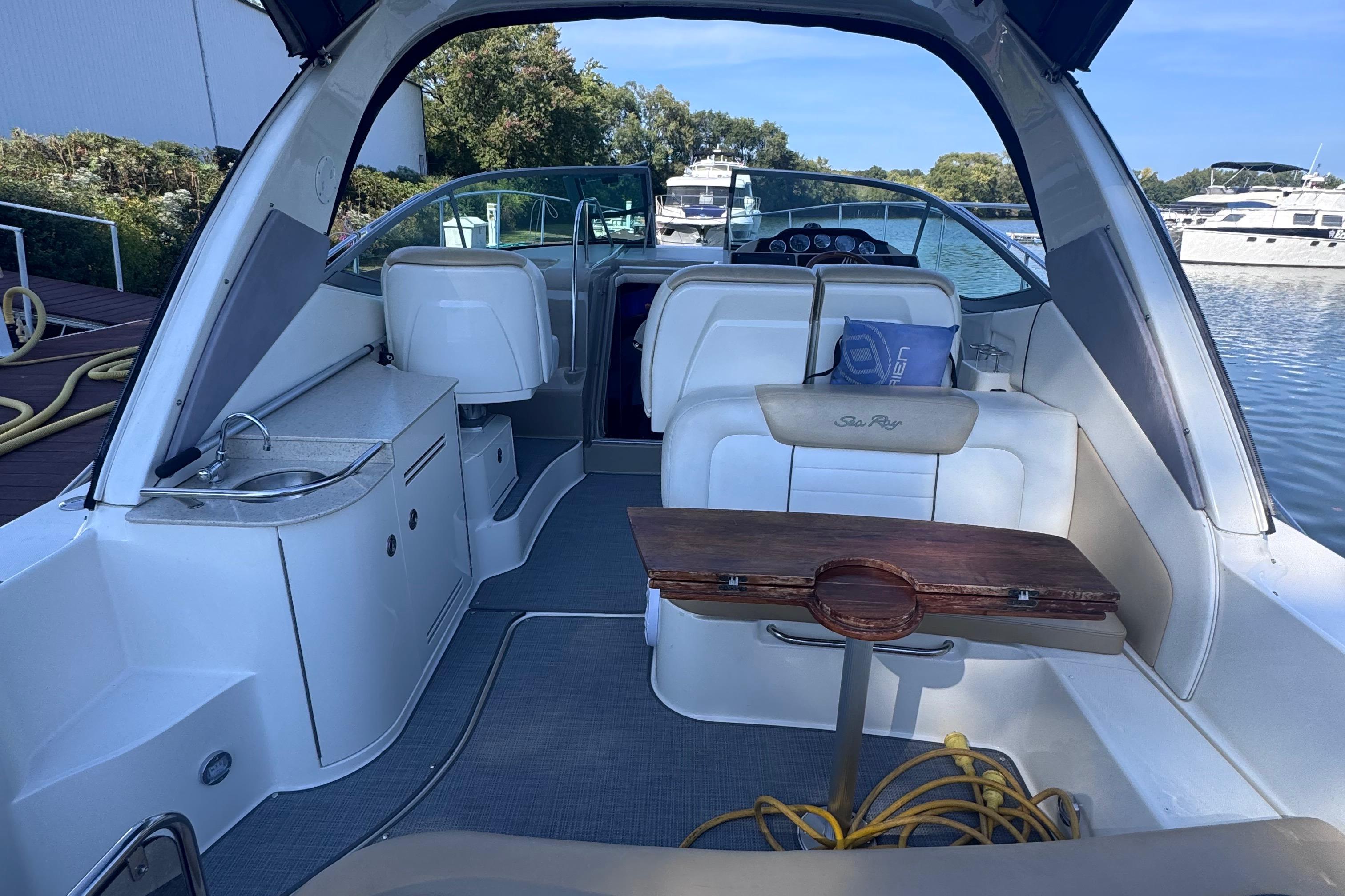 2008 Sea Ray 350 Sundancer interior with seating, table, and kitchenette by the water.