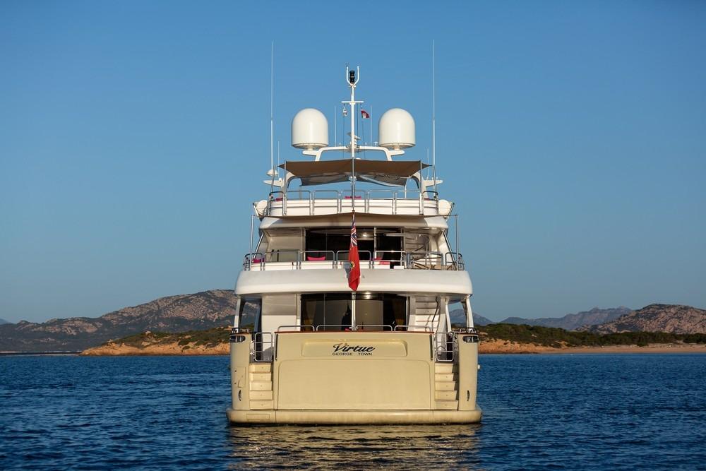 Rear view of 2008 Benetti Classic 120 yacht on calm sea with scenic coastline.