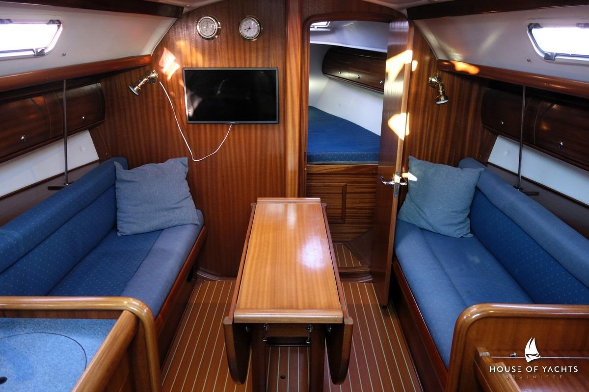 Interior of 2003 Bavaria 32 yacht with wooden finish and blue seating.