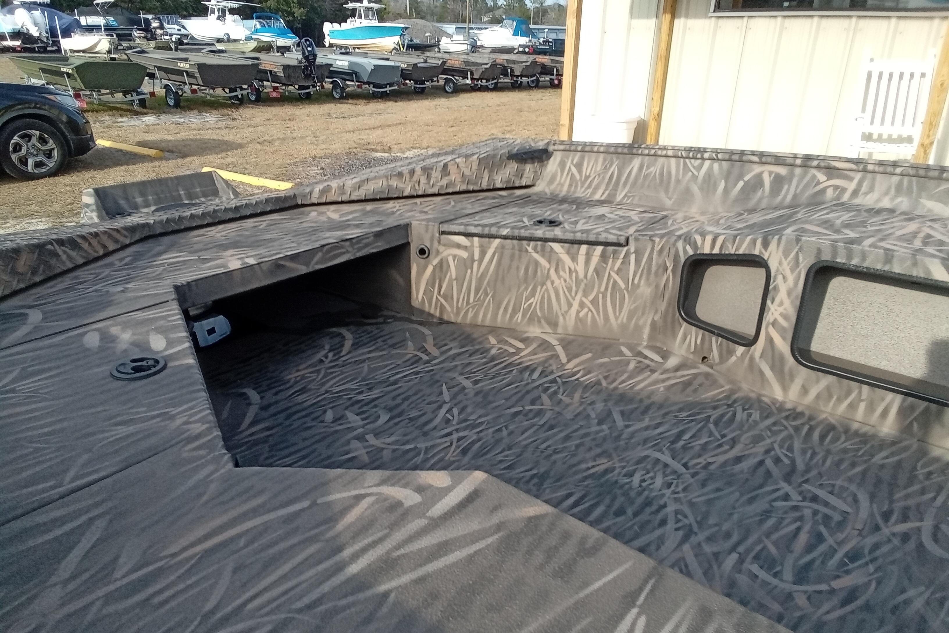 2026 Alweld 1756 Invader boat interior with camo pattern, parked among other boats.