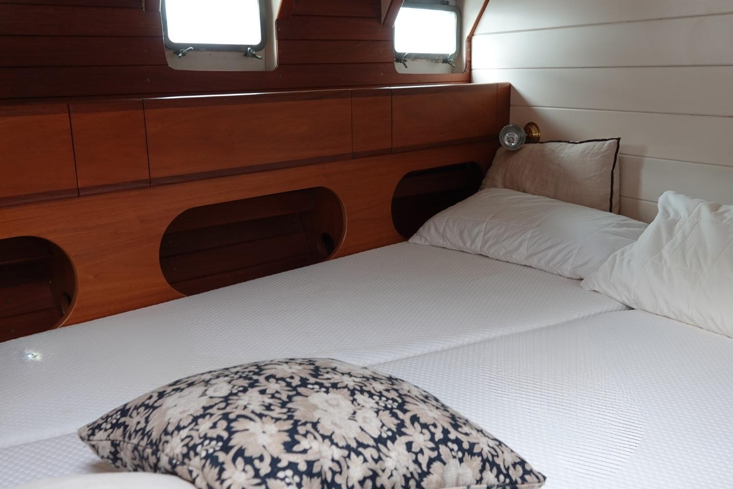 Cozy cabin interior of a 1973 Custom Steel Ketch with wooden paneling and bedding.