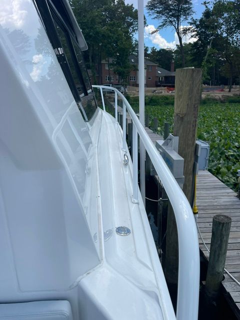 Side view of a white boat at a dock with green vegetation in the background.
