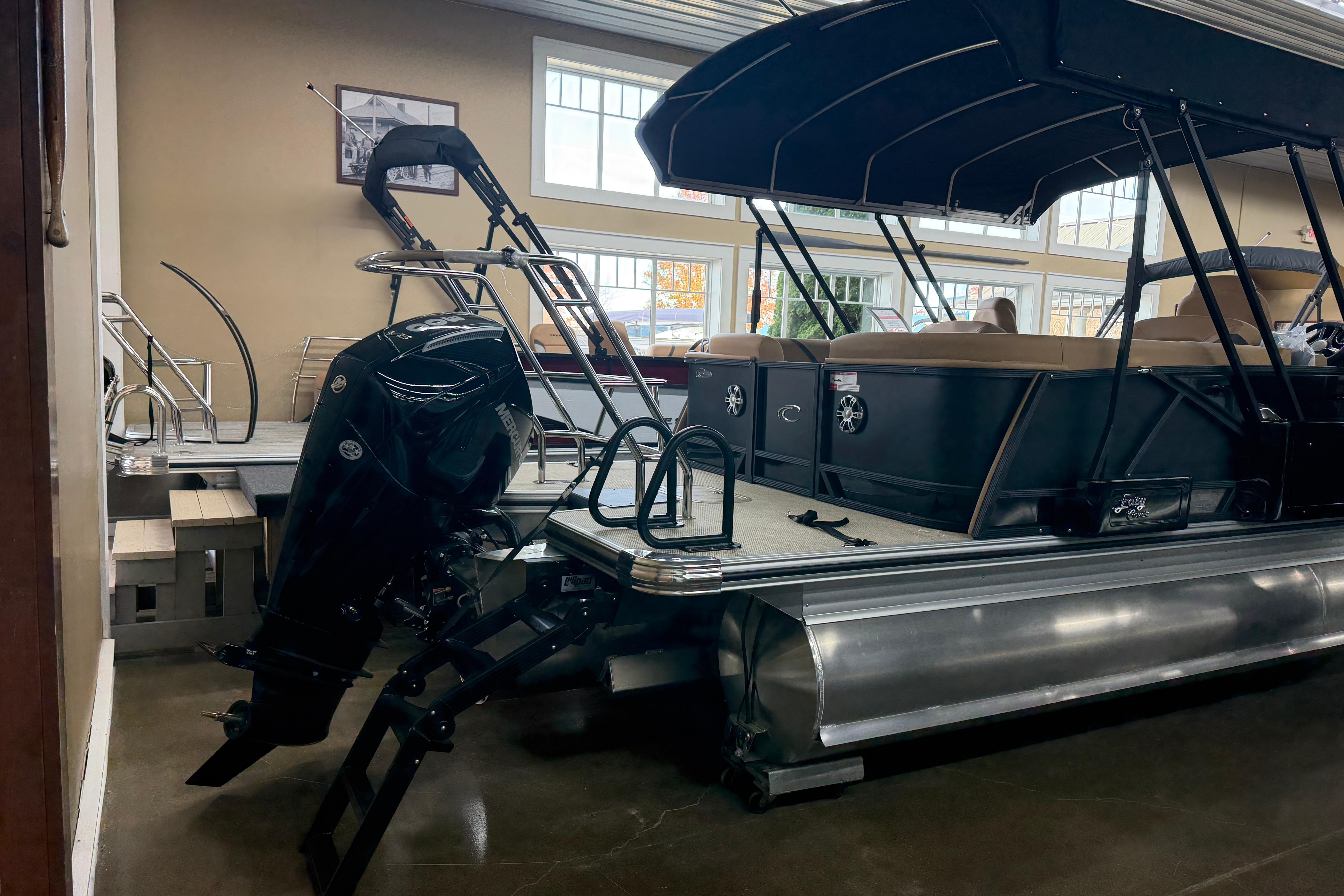 2026 Crest Caribbean 230 SLC pontoon boat with outboard motor in showroom.