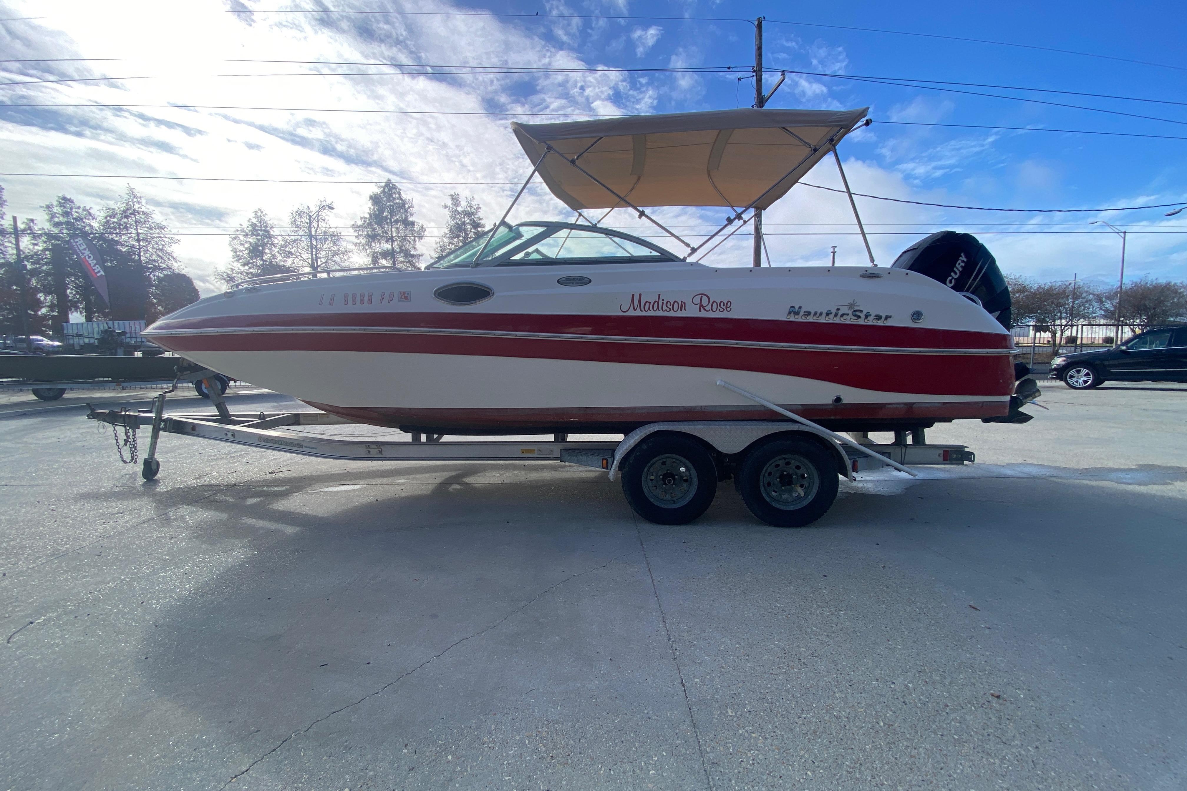 2007 NauticStar 230DC Sport Deck boat on trailer, red and white design, outdoor setting.