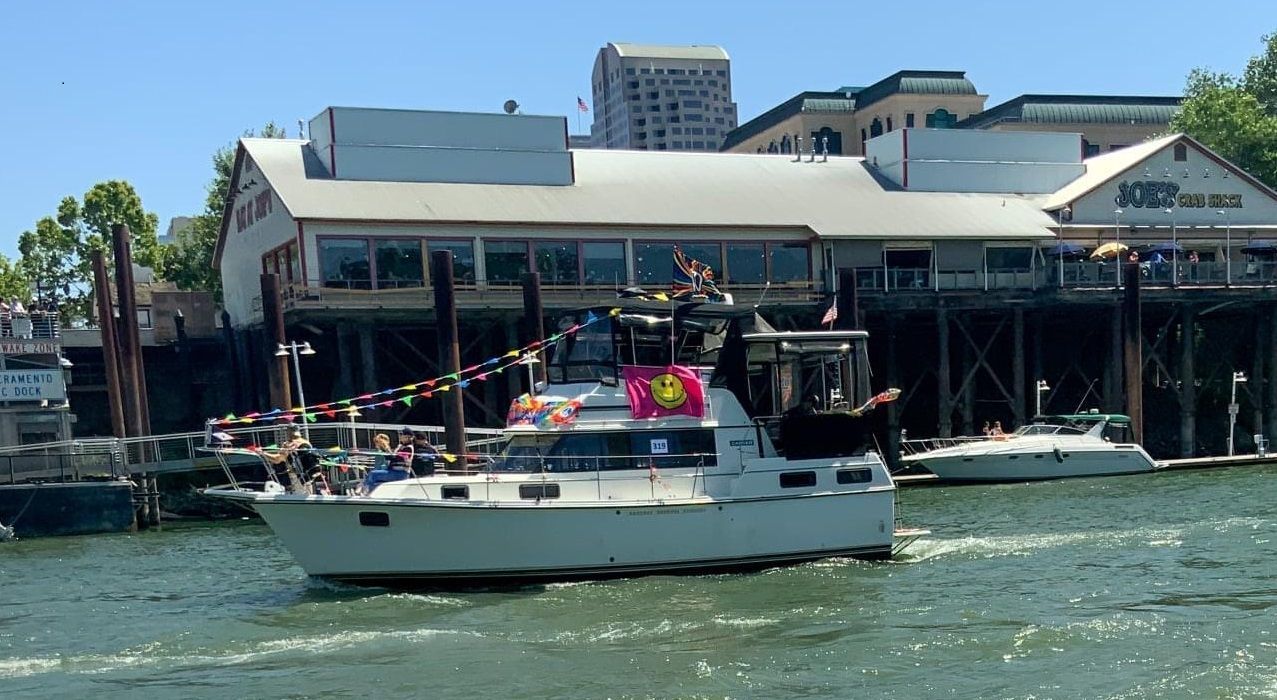A 1988 Carver 3607 Aft Cabin Motor Yacht on a river, passing by a building.